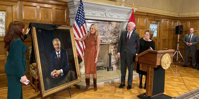 Arkansas Gov. Asa Hutchinson and first lady Susan Hutchinson look on as their granddaughter, Jaella Wengel, left, and daughter, Sarah Wengel, center, unveil the governor’s official portrait on Tuesday, Jan. 3, 2023, at the state Capitol in Little Rock, Ark. Hutchinson left office on Jan. 10 after serving eight years as governor. (AP Photo/Andrew DeMillo)