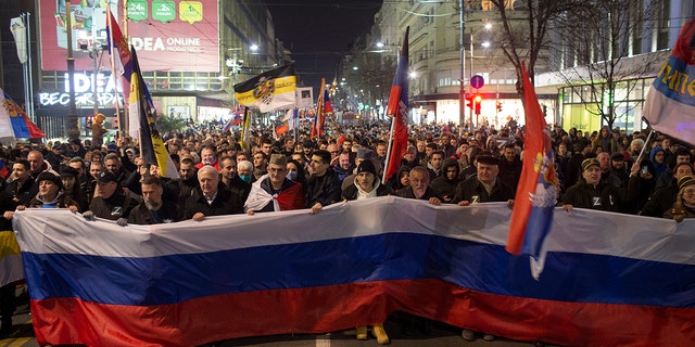 People hold a large Russian flag during a rally in support of Russia in Belgrade, Serbia, Friday, March 4, 2022. Serbia rejects calls from the European Union to join sanctions against Russia, citing national interests.