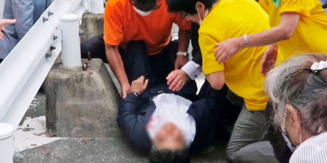 Japan’s former Prime Minister Shinzo Abe, center, falls on the ground in Nara, western Japan Friday, July 8, 2022. 