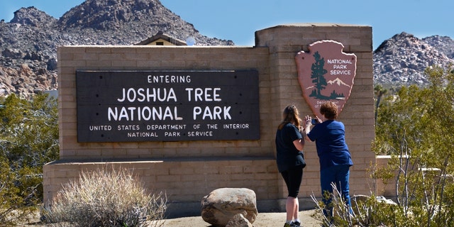 Tourists take souvenir pictures of the National Park Service sign welcoming visitors to Joshua Tree National Park in California on Feb. 27, 2019.