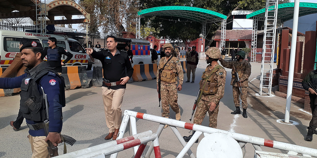 Army soldiers and police officers clear the way for ambulances rushing toward a bomb explosion site.