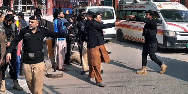 Police officers clear the way for ambulances leaving after carrying wounding people from bomb explosion site.