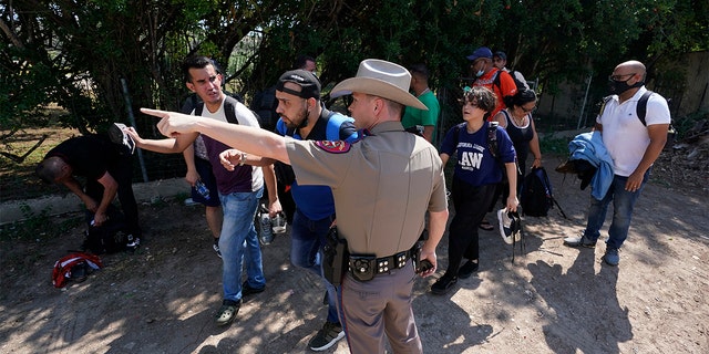 A Texas Department of Public Safety officer in Del Rio, Texas directs a group of migrants who crossed the border and turned themselves on June 16, 2021.