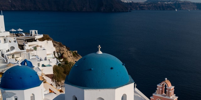 A view of the town of Oia with its lime-washed houses and churches with blue domes on Santorini in the Aegean Sea.