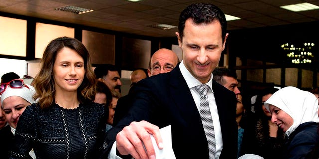 Syrian President Bashar Assad casts his ballot in the parliamentary elections, as his wife Asma, stands next to him, in Damascus, Syria.
