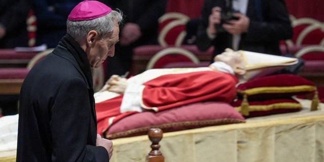 VATICAN - 2023/01/02: Archbishop Georg Gänswein prays in front of the body of Pope Emeritus Benedict XVI at St. Peter's Basilica. The Vatican announced that Pope Benedict died on December 31, 2022, aged 95. His funeral was held on January 5, 2023. 