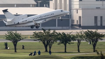 Golfers walk the fairways as a jet takes off.