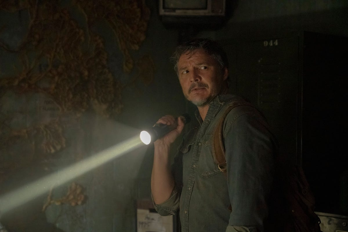 Pedro Pascal holds a flashlight in a dark space in The Last of Us.