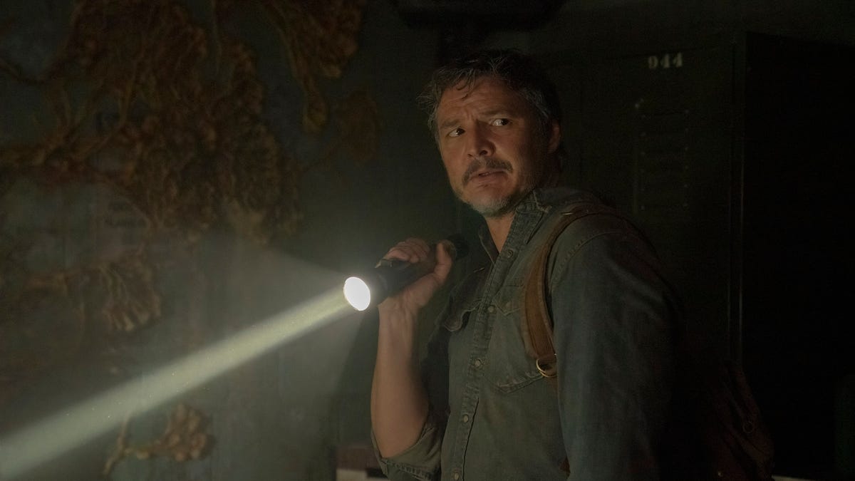 Pedro Pascal holds a flashlight in a dark space in The Last of Us