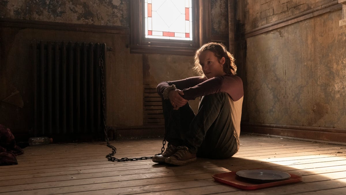 Ellie sits alone in a dirty room, chained to a radiator, in The Last of Us