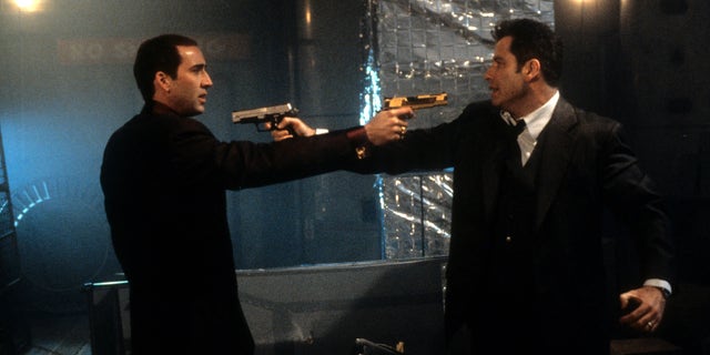 Nicolas Cage and John Travolta aiming guns at each other in a scene from "Face/Off."
