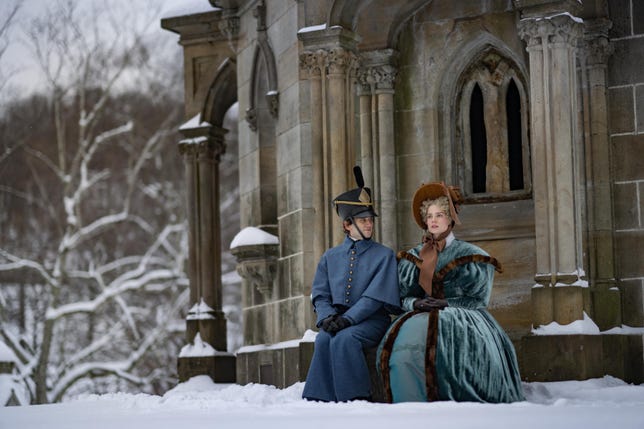 Edgar and Lea sitting outside in the snow next to a building