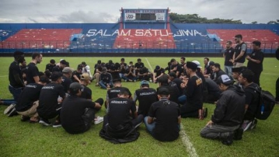 Players and officials from Arema Football Club gather to pray on the pitch for victims of the stampede at Kanjuruhan stadium in Malang.