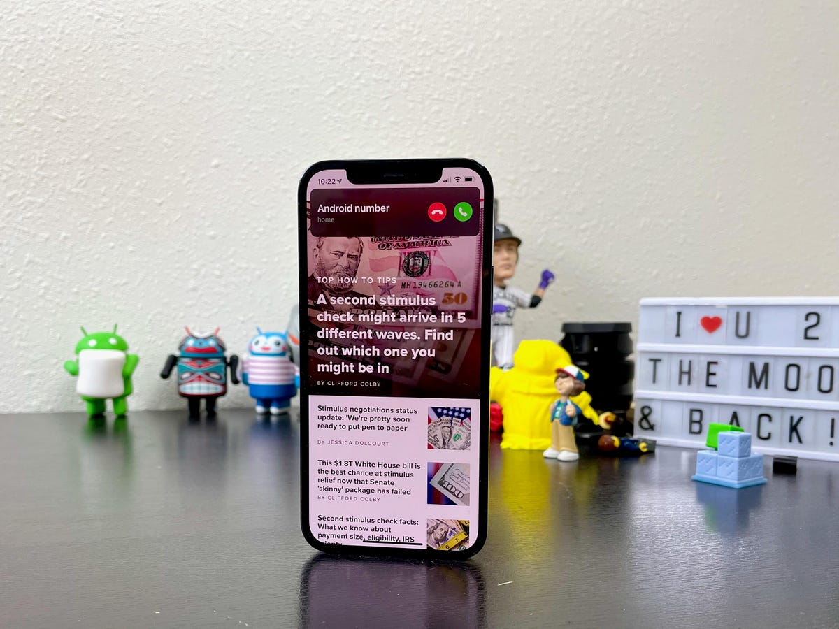 A phone showing a notification bar at the top of the screen, propped up on a table in front of various toys