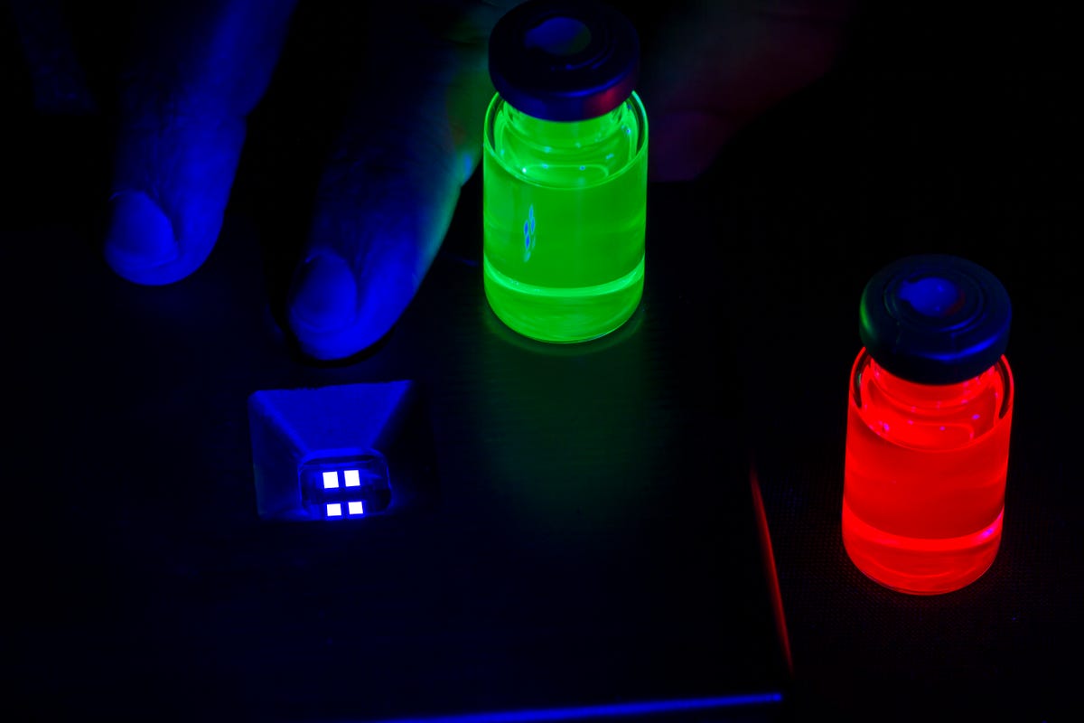 Red and green vials of photoluminescent quantum dots next to a prototype blue electroluminescent QD.