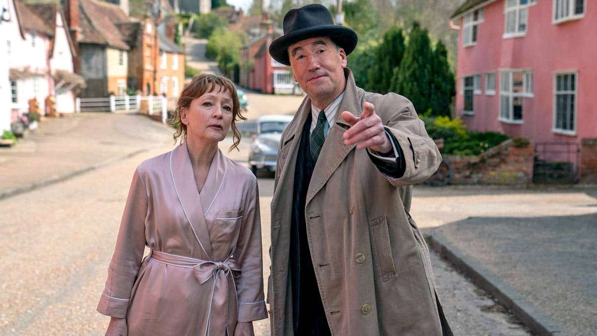 Lesley Manville stands next to a pointing Tim McMullan on a street in the fictional town of Saxby-on-Avon