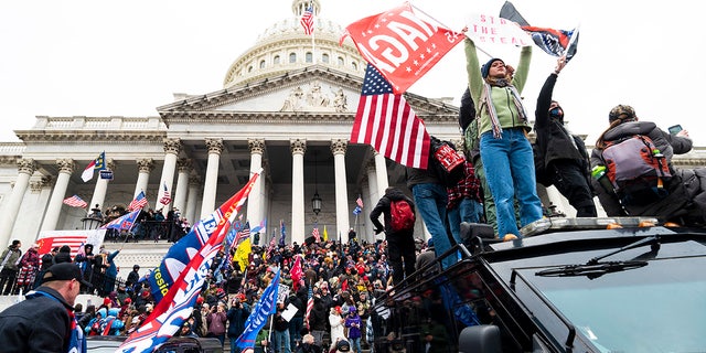 Trump supporters stand on the U.S. Capitol Police armored vehicle as others take over the steps of the Capitol on Wednesday, Jan. 6, 2021.