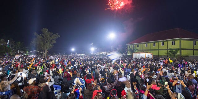 Fireworks light up the sky as people react while they celebrate after counting down to the new year in Kampala, Uganda, on Jan. 1, 2023. A stampede occurred just before the firework show leaving 10 dead. 