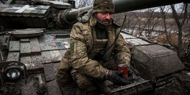 A Ukrainian serviceman holds a homemade trench candle to light and heat makeshift shelters, sitting on a tank on the frontline near Kreminna, Lugansk region, on January 12, 2023, amid the Russian invasion of Ukraine. 