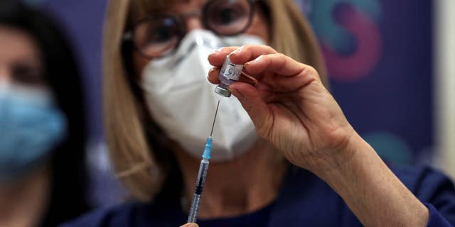 A nurse prepares to administer a COVID vaccine.