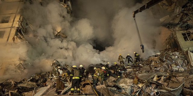 Emergency workers clear the rubble after a Russian rocket hit a multistory building, leaving many people under debris, in the southeastern city of Dnipro, Ukraine, on Saturday, Jan. 14.