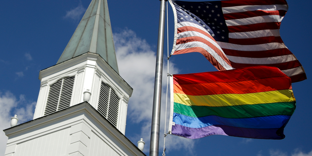 In this April 19, 2019, file photo, a gay pride rainbow flag flies along with the U.S. flag in front of the Asbury United Methodist Church in Prairie Village, Kansas.