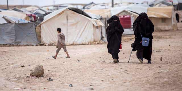 Women walk in the al-Hol camp that houses some 60,000 refugees, including families and supporters of the Islamic State group, many of them foreign nationals, in Hasakeh province, Syria, May 1, 2021.