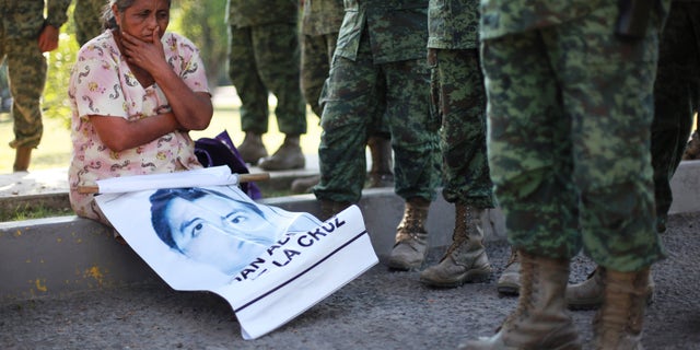 The mother of missing college student Adan Abarajan de la Cruz sits at the foot of soldiers outside a military base during a protest by the families of 43 missing students over the army's alleged responsibility or lack of response to the students disappearance in Iguala, Mexico. 