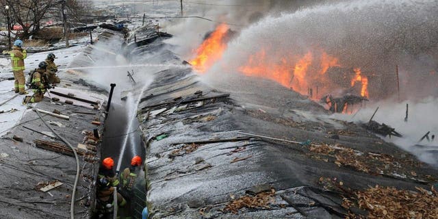 Firefighters battle a fire at Guryong village in Seoul, South Korea, Friday, Jan. 20, 2023. About 500 South Koreans were forced to flee their homes after a fire spread through a low-income neighborhood in southern Seoul on Friday morning and destroyed dozens of homes.  