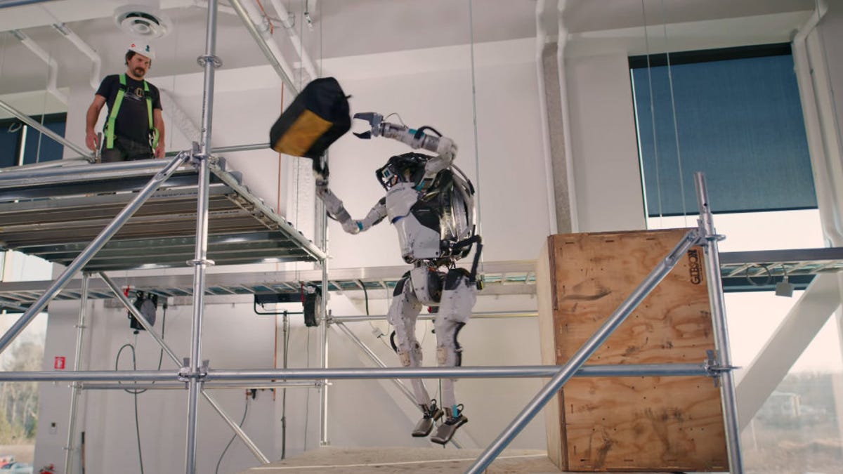 Boston Dynamics Atlas robot spins and tosses a tool bag from a platform to a higher platform.