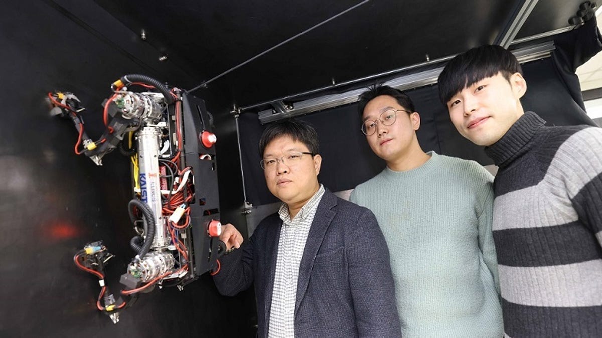 Marvel four-legged robot is attached to a wall with three researchers standing next to it.