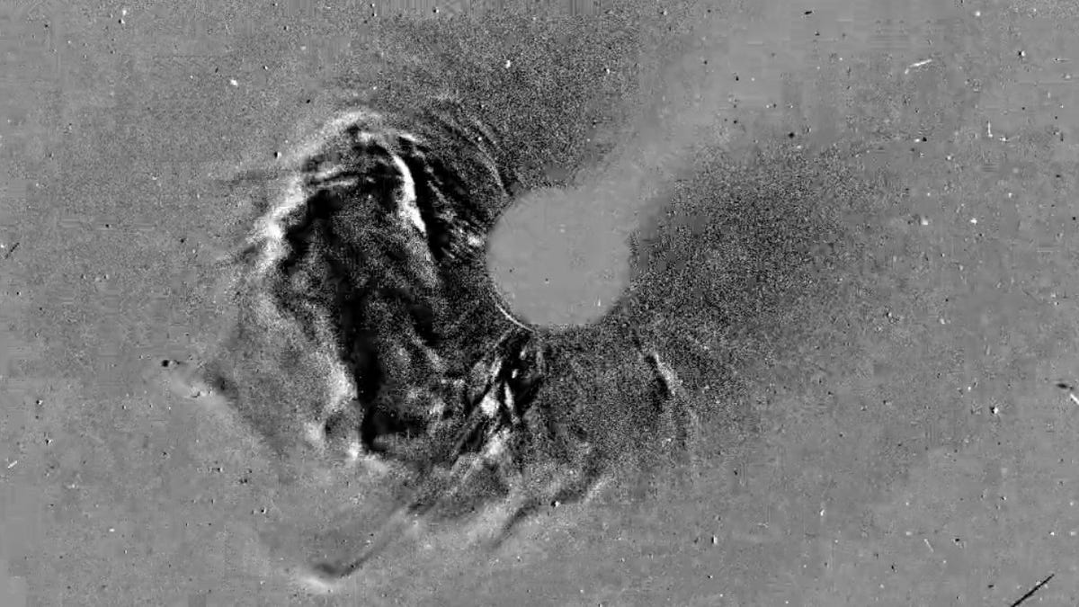 Black and white image shows curving outburst of material from the sun, which is blocked out to better show the CME.