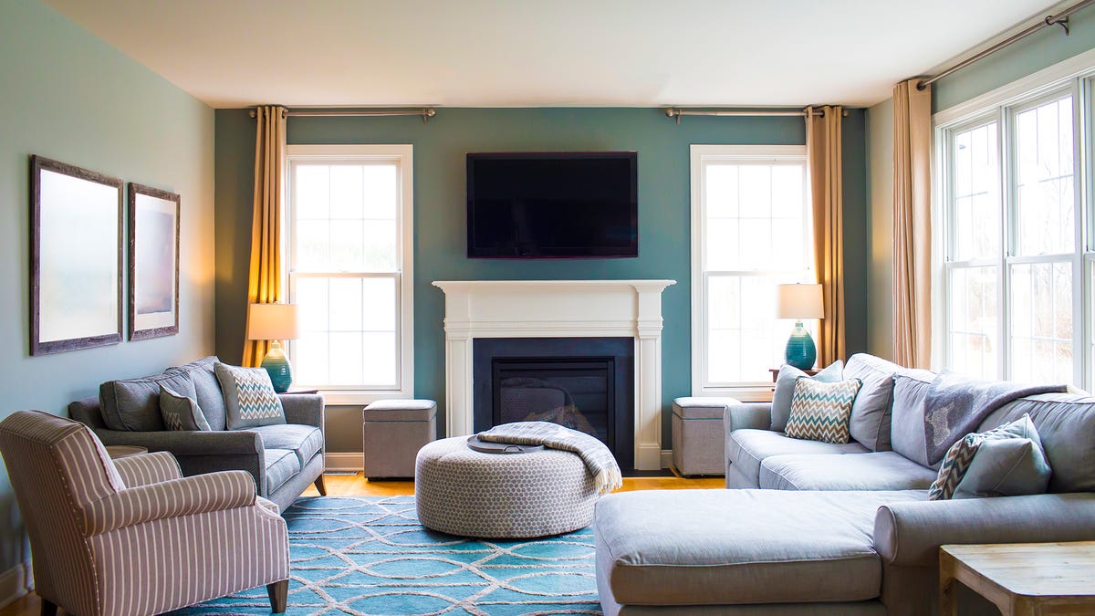 A stylish, well-lit living room with many windows and a TV mounted above a fireplace.