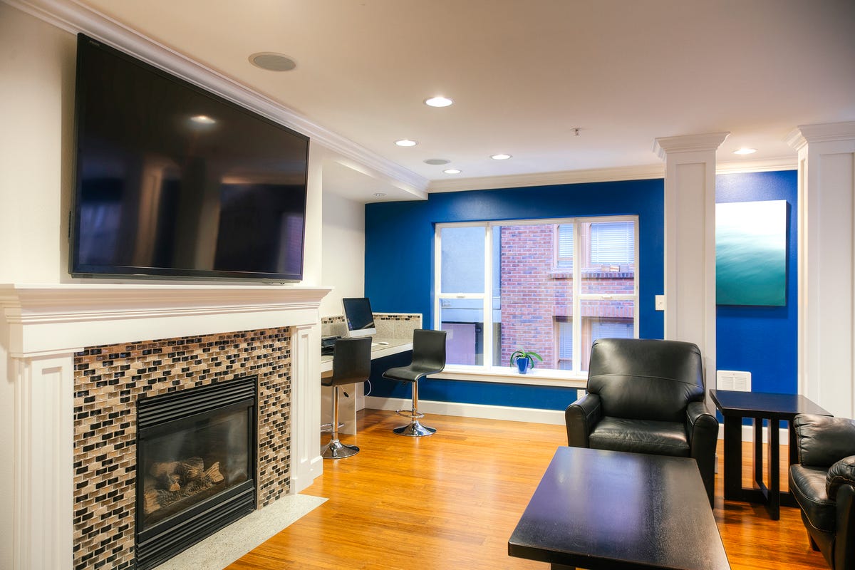 A small living room with a large TV mounted over a fireplace.