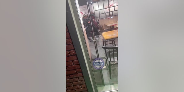In the clip, police storm the fast food chain and can be seen challenging the group of "male youths".