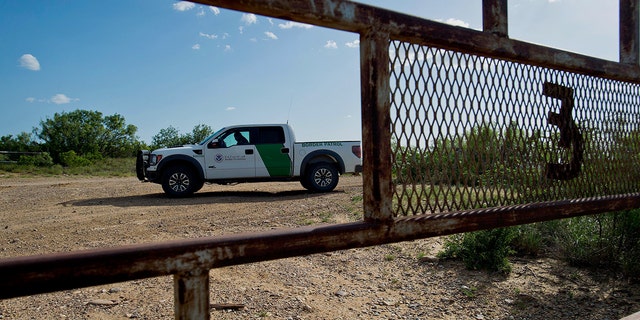 A U.S. Border Patrol agent sits in a truck on a road outside a ranch gate near Carrizzo Springs, Texas, U.S.