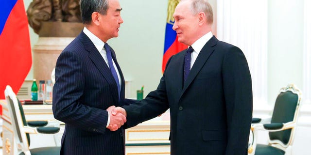Russian President Vladimir Putin greets Chinese Communist Party's foreign policy chief Wang Yi during their meeting at the Kremlin in Moscow, Russia, Wednesday, Feb. 22, 2023.