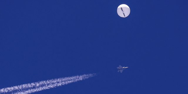 A large balloon drifts above the Atlantic Ocean, just off the coast of South Carolina, with a fighter jet and its contrail seen below it, on Saturday, Feb. 4.