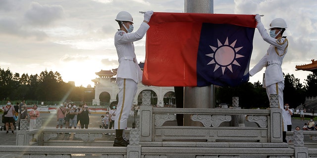 FILE - Two soldiers fold the national flag during the daily flag ceremony in Liberty Square of Chiang Kai-shek Memorial Hall in Taipei, Taiwan, Saturday, July 30, 2022. 