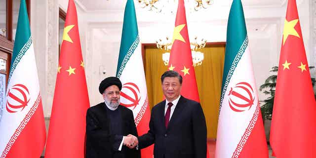 In this photo released by the official website of the office of the Iranian Presidency, President Ebrahim Raisi, left, shakes hands with his Chinese counterpart Xi Jinping in an official welcoming ceremony in Beijing, Tuesday, Feb. 14, 2023. 