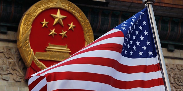 An American flag is flown next to the Chinese national emblem during a welcome ceremony at the Great Hall of the People in Beijing Nov. 9, 2017. 