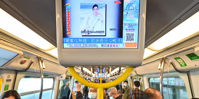 People watch a screen on a train showing news about Hong Kong model and influencer Abby Choi on Feb. 27, 2023 in Hong Kong. Choi's partial remains were found by the police at a house on Feb. 24. Hong Kong police have made four arrests for the murder and dismemberment of the 28-year-old model after a financial dispute with her ex-husband's family, authorities said.