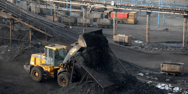 A worker watches a bulldozer unload coal at a coal mine in Huaibei in central China's Anhui province.