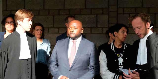 Mpanzu Bamenga, center, stands with his legal team outside a courtroom at The Hague District court in the Netherlands on Sept. 22, 2021. The court banned the Netherlands' military police from using racial profiling to select people for identity checks at borders on Feb. 14, 2023.