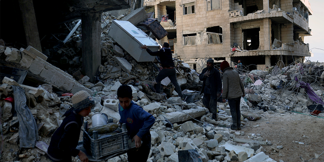People remove furniture and household appliances out of a collapsed building after a devastating earthquake rocked Syria and Turkey in the town of Jinderis, Aleppo province, Syria, Tuesday, Feb. 7, 2023.