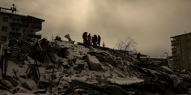 People try to reach people trapped under the debris of a collapsed building in Malatya, Turkey, Tuesday, Feb. 7, 2023.