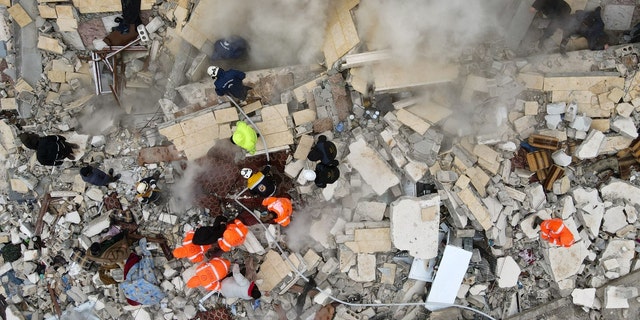 This aerial view shows residents helped by bulldozers, searching for victims and survivors in the rubble of collapsed buildings, following an earthquake in the town of Sarmada in the countryside of the northwestern Syrian Idlib province, early on Feb. 6, 2023. 