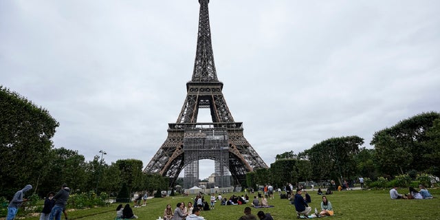 People relax at the Champ de Mars garden next to the Eiffel Tower in Paris, July 16, 2021.