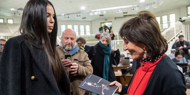 Karima El Mahroug, aka Ruby Rubacuori, one of the girls who attended the infamous Bunga Bunga parties, presents her book to prosecutor Tiziana Siciliano, right, in Italy, on Feb. 15, 2023. 