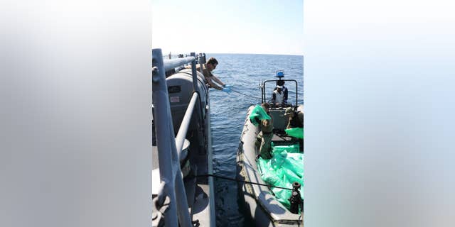 U.S. Navy servicemen transfer 2,000 assault rifles confiscated from an Iranian smuggling vessel. (US Navy)